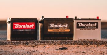 All three tiers of Duralast batteries sitting on top of the edge of a road in the desert.