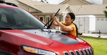 Woman changing the wiper blades on a Jeep.