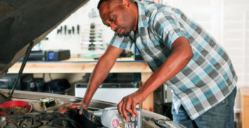 Man pouring STP synthetic oil into his car's engine.