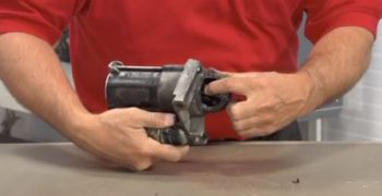 A man pointing at the gear inside of a starter motor.