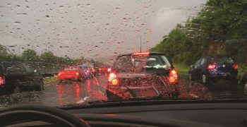 A driver's seat view of cars driving on the freeway in the rain.