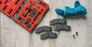 Brake pads and a brake tool sitting on a wood floor, waiting to be installed.