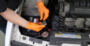 orange gloves showing how to install new battery and clamp to side post battery