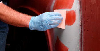 Person applying glaze to a dent that has been smoother over with body filler