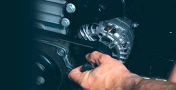 a man using a rachet to unbolt an alternator pulley